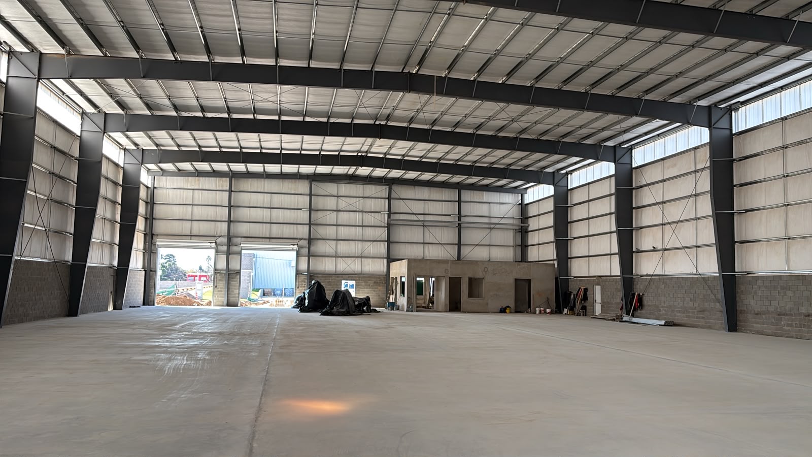 Interior de la nave con piso de hormigón terminado y los portones de carga al fondo, Parque Industrial Reconquista